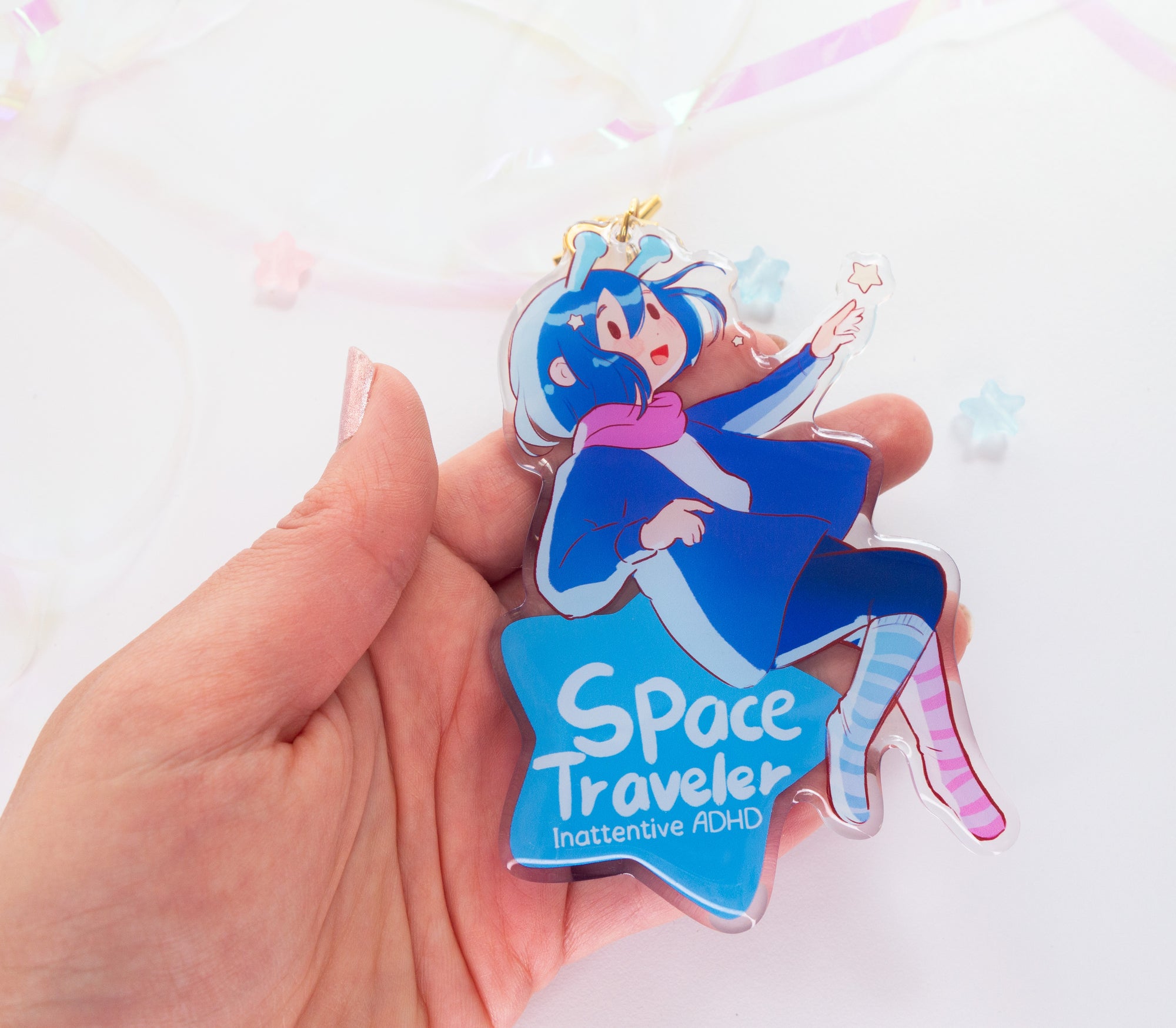 Hand holding a 'Space Traveler' ADHD Alien awareness charm against a light background