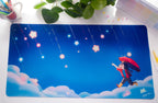 Illustrated desk pad with a character holding an umbrella under a starry sky, placed on a desk with stationery items.