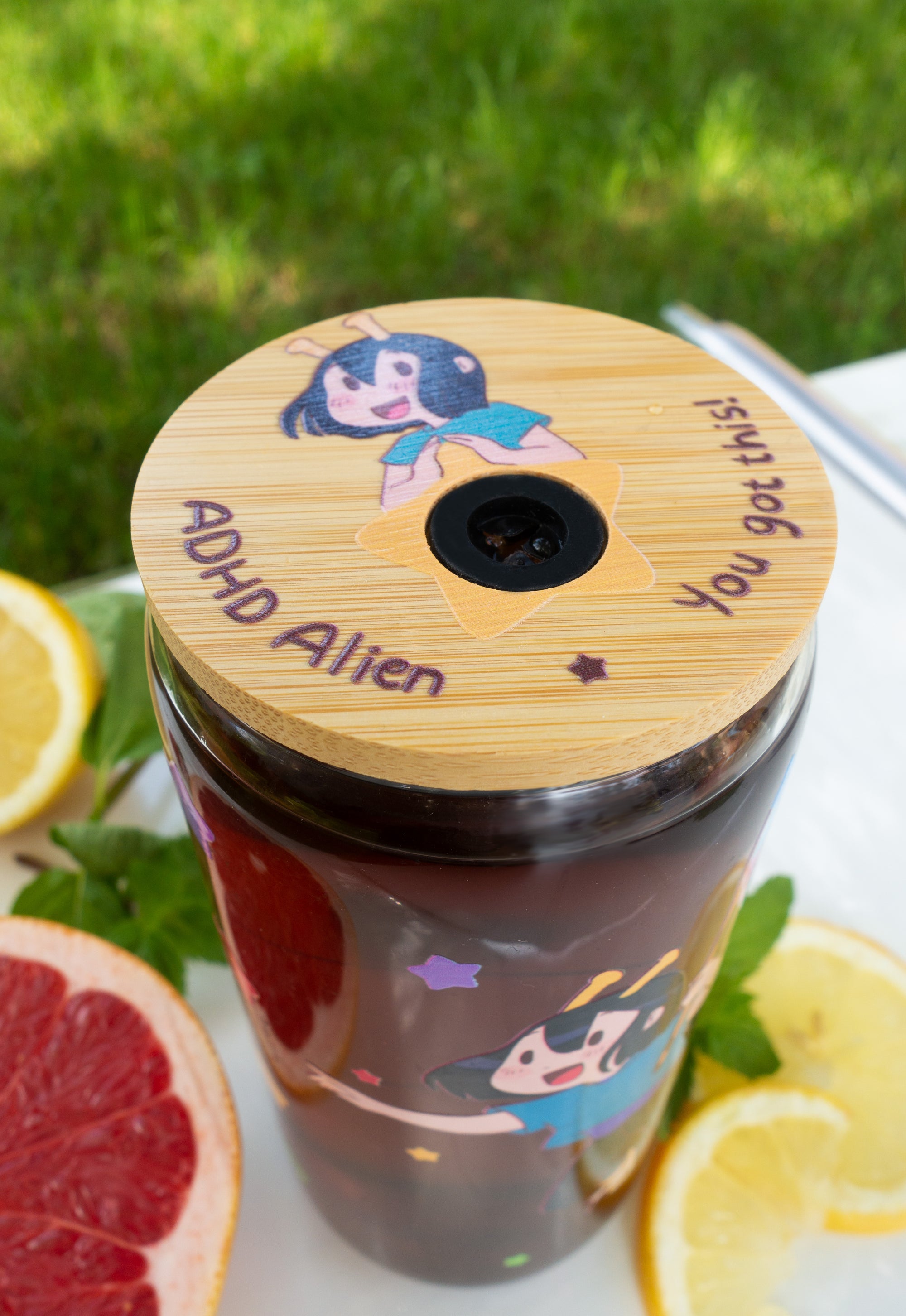 Tumbler with ADHD Alien cartoon character print and bamboo lid on a table with fruits