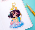 ADHD Alien character charm with 'Embracing ADHD' text on a notebook with stationery items.