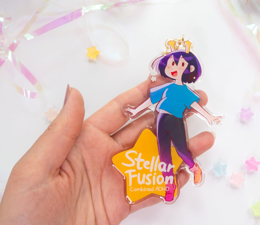 Hand holding the acrylic charm with 'Stellar Fusion' text on the star part over a white background