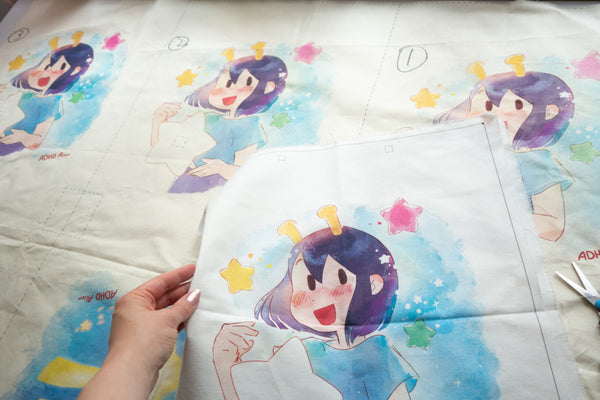 Prototype prints of the totebag design with a hand holding one prototype. - Making of image 2