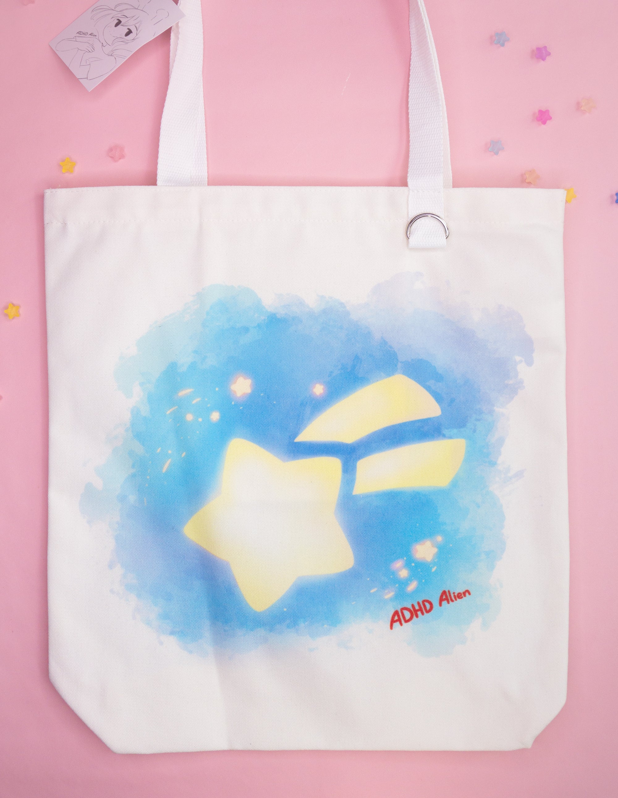 Tote bag with aquarell star design and 'ADHD Alien' text on a pink background