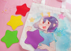 Tote bag with the ADHD Alien character  on a pink background with colorful star-shaped patches in 4 different colors.