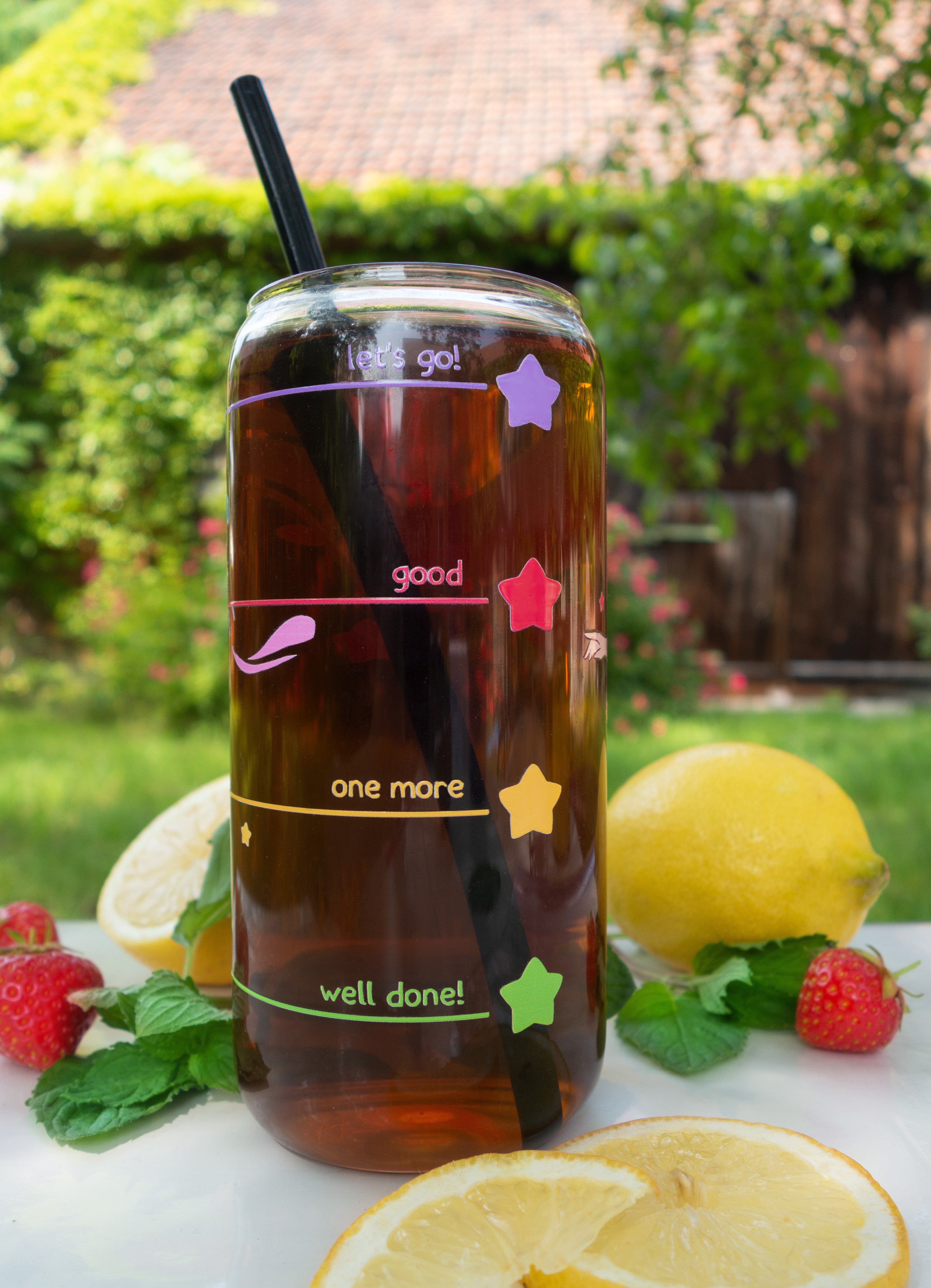 Glass of iced tea with drink level markers on a table outdoors with lemons and strawberries.