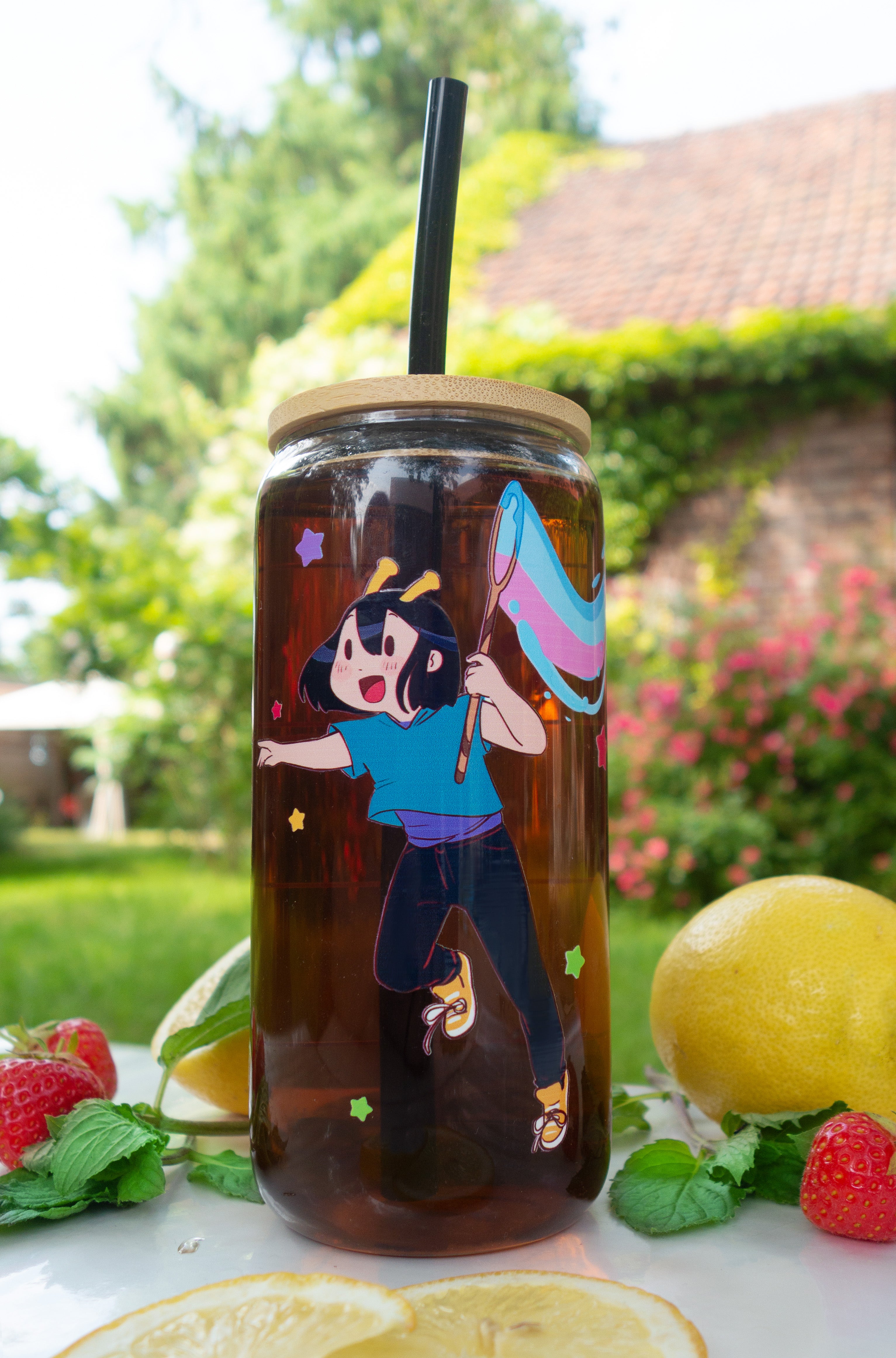 Tumbler with ADHD Alien character print on a table outdoors with lemons and berries.